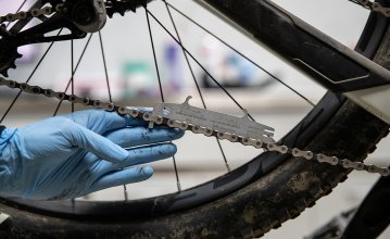 A mechanic measures the condition of the bike chain with a chain wear indicator. 