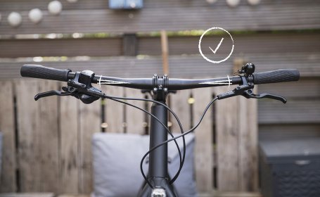 Frontal betrachtet: Der Lenker ist so rotiert, dass die Lenkerenden nach oben zeigen. Das ist für die Hand-Haltung ergonomisch korrekt und die ab Werk eingestellte Haltung.