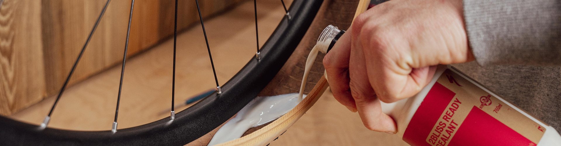 Main versant du liquide préventif tubeless dans un pneu de vélo monté sur une jante, gros plan lors d’une conversion en tubeless.