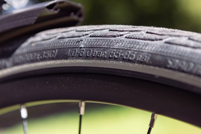 Close-up photo of a bicycle tyre sidewall. The permitted pressure range is in focus.