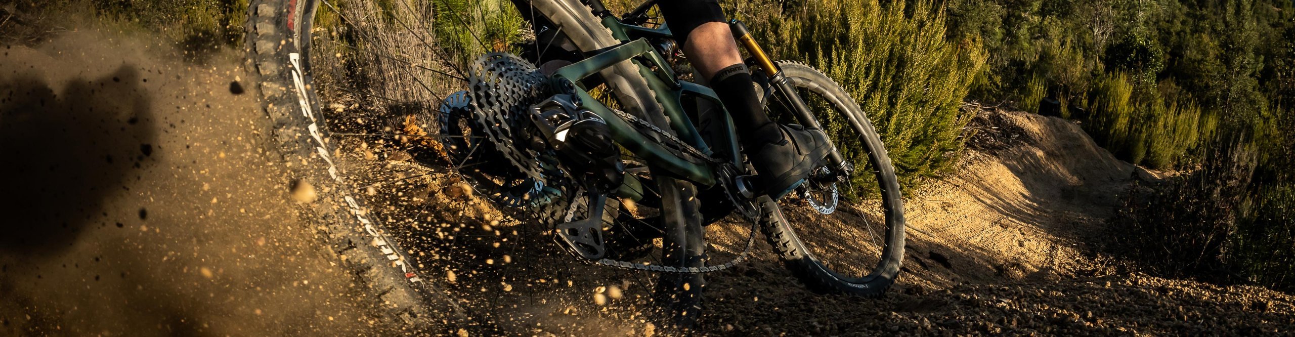 Shimano MTB Bremsen im Einsatz: Mountainbiker fährt eine staubige Kurve auf anspruchsvollem Trail