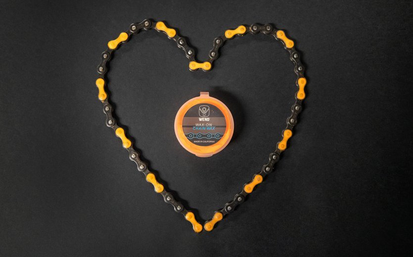 A chain is laid out in the shape of a heart. The chain is coloured orange with chain wax. 