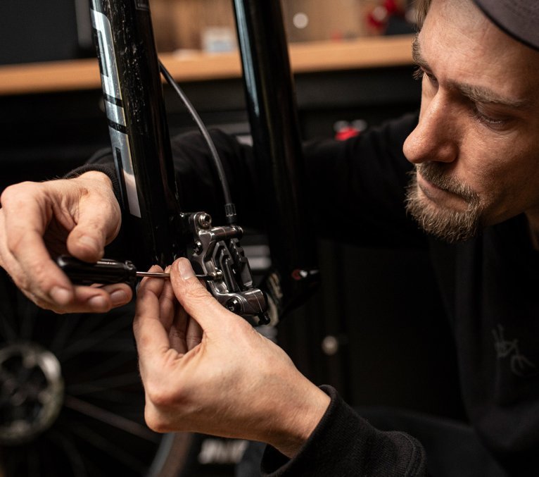 Zweiradmechaniker schraubt an einem Bremssattel