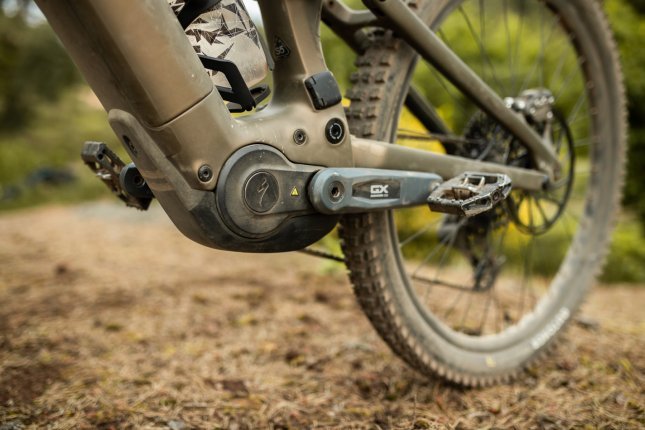 Detailfoto vom Tretlager- und Motorbereich eines bronze-grünen Specialized Turbo Levo 4 im Wald.