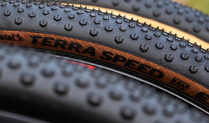 Nahaufnahme mehrerer Gravelbike Reifen mit markantem Profil und brauner Seitenwand, übereinander angeordnet, Fokus auf Struktur und Lauffläche.