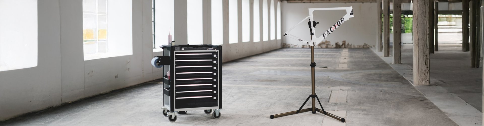 Carro de herramientas y soporte de montaje en una nave industrial vacía con grandes ventanas.