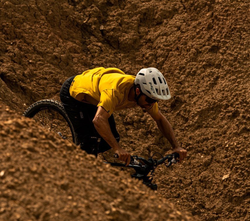 Mountainbiker mit weißem MET Helm und gelbem Trikot auf technisch anspruchsvollem Trail in felsigem Gelände