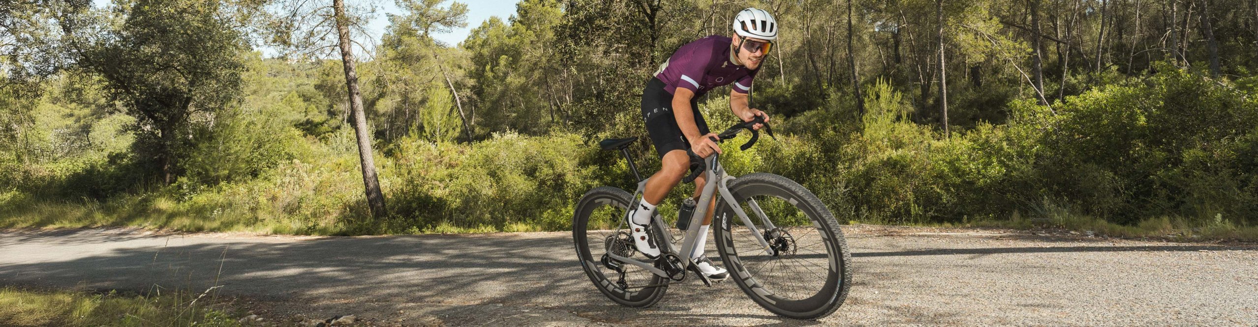 Gravel cyclist rides an OPEN WI.DE with Zipp wheels on a gravel road through the forest.