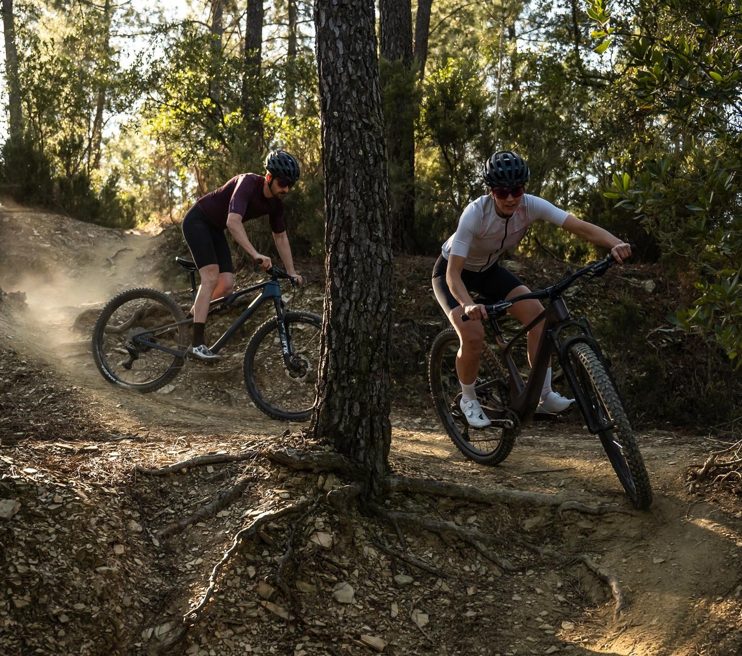 Transmissions VTT Shimano en action avec deux vététistes sur un sentier technique en forêt avec poussière et racines