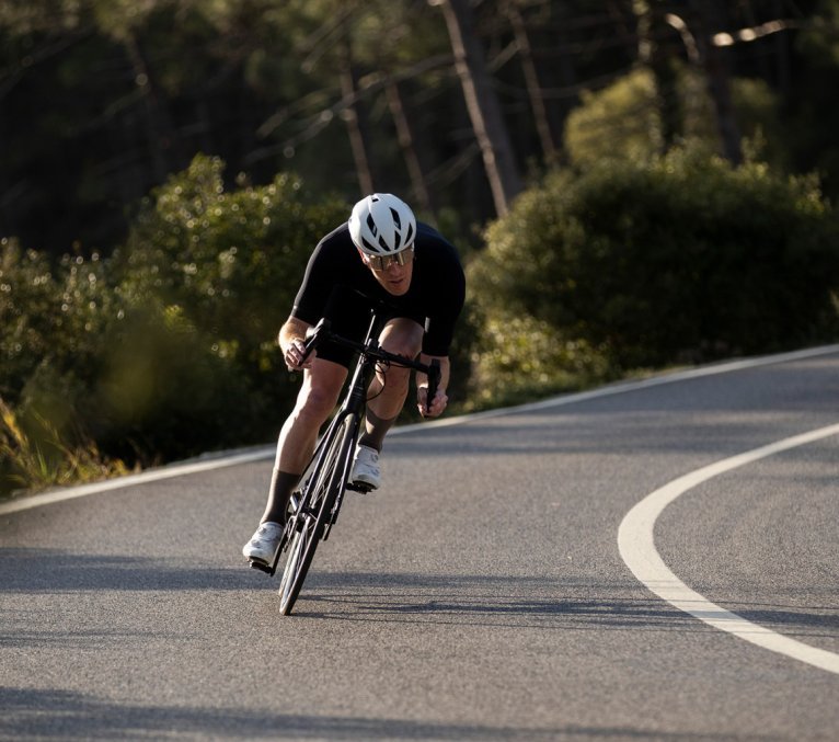 Sergej aus dem bc Service-Team fährt auf einem Rennrad eine Straße hinab. Er hat eine aerodynamische Position eingenommen.