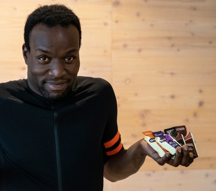 A man holds various energy gels up to the camera.