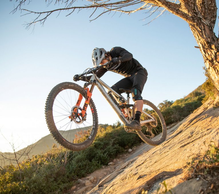 Christian from bc Product Management rides on the rear wheel of his RAAW bike over rocky ground.