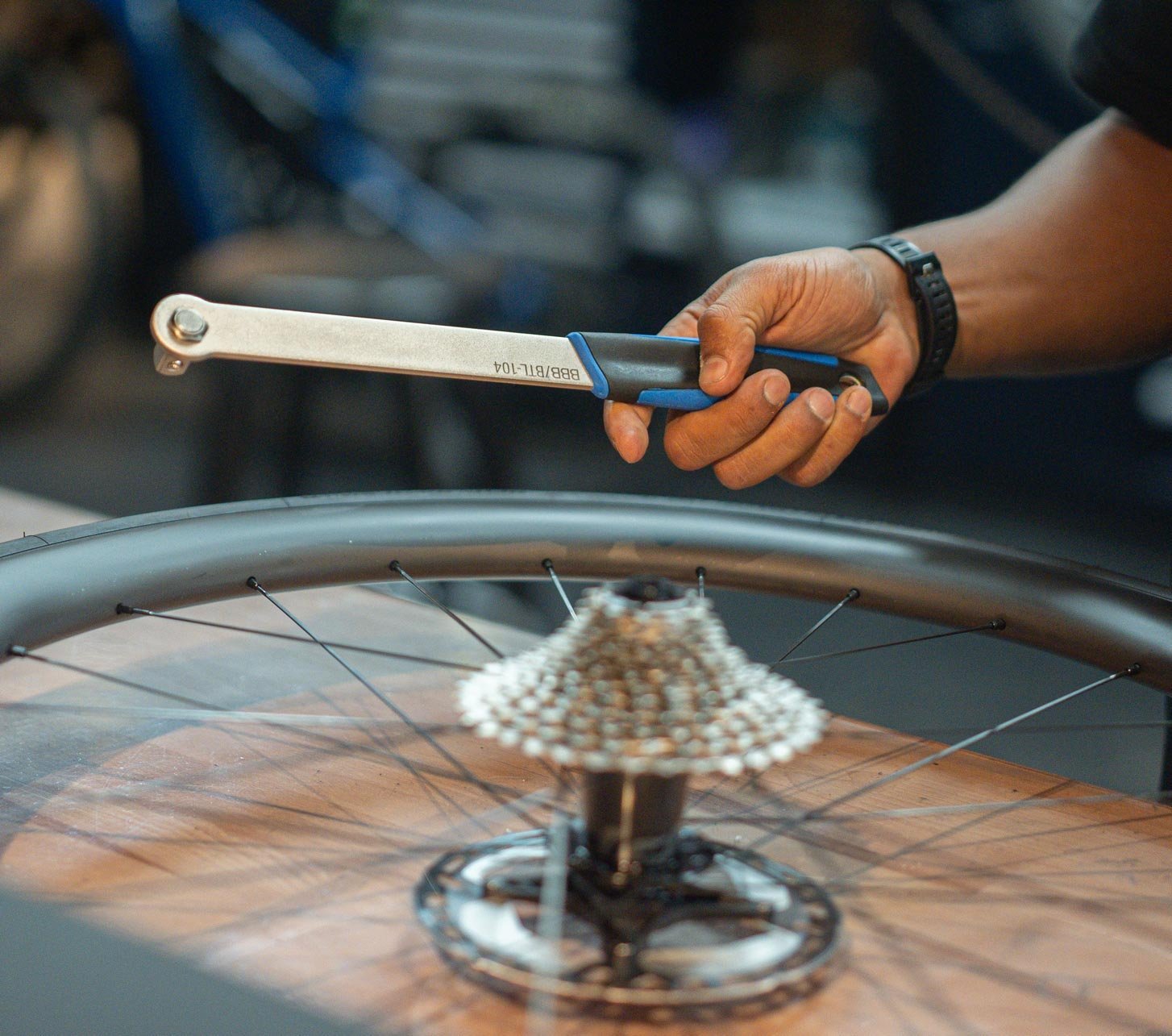 BBB Fahrradwerkzeug in der Hand eines Mechanikers über einem Laufrad mit Kassette in der Fahrradwerkstatt.