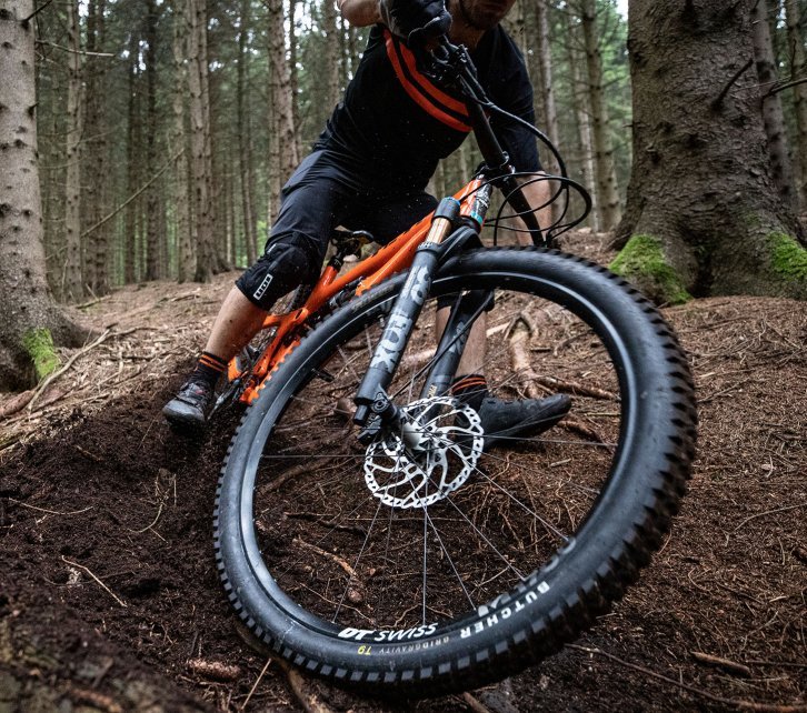 Christian from bc Product Management rides a Yeti MTB downhill along a forest path. The focus of the picture is on the front wheel and tyre of his bike. The tyre is the Butcher from Specialized.