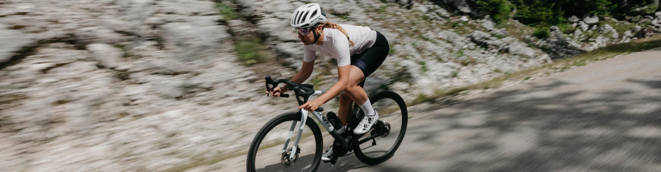 Ciclista de carretera con ropa de ciclismo Scott sobre una bicicleta de carretera Scott en una carretera de montaña