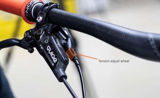 The tension adjust screw is visible. This is located directly on the handlebars at grip height on the MTB. An arrow points to the exact spot.