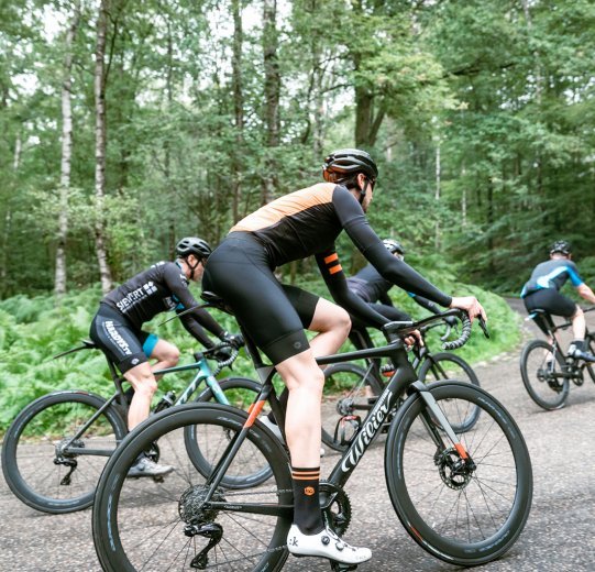 Un groupe de cyclistes de route s'engage dans une montée. Tous les vélos sont équipés de groupes de transmission Shimano Dura Ace Di2.