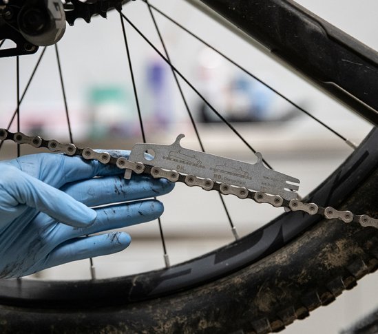 Der Mechaniker ermittelt mit einer Kettenverschleißlehre Längung einer SRAM-Kette. 