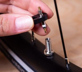 Detail photo: A hand removing the valve core from a Presta bicycle valve