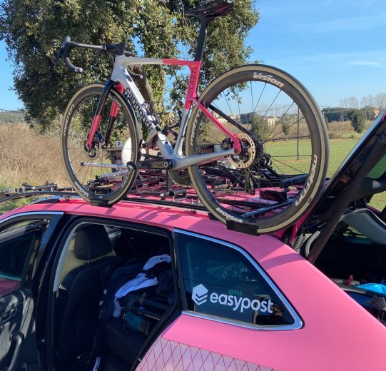 The photo shows a Cannondale SuperSix EVO in the EF Education-EasyPost colours on the roof rack of a team vehicle. 