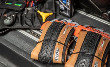 Une paire de pneus VTT Maxxis Ikon 29" est prête à être montée. En arrière-plan, on peut voir des outils pour pneus adaptés et du fluide d'étanchéité.