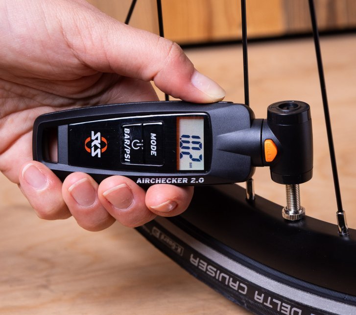 Close-up: An SKS Airchecker is held against an installed bicycle valve.