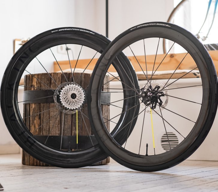 Zwei Black Inc Carbonlaufräder für Rennräder lehnen in einem hellen, gemütlichen Showroom.