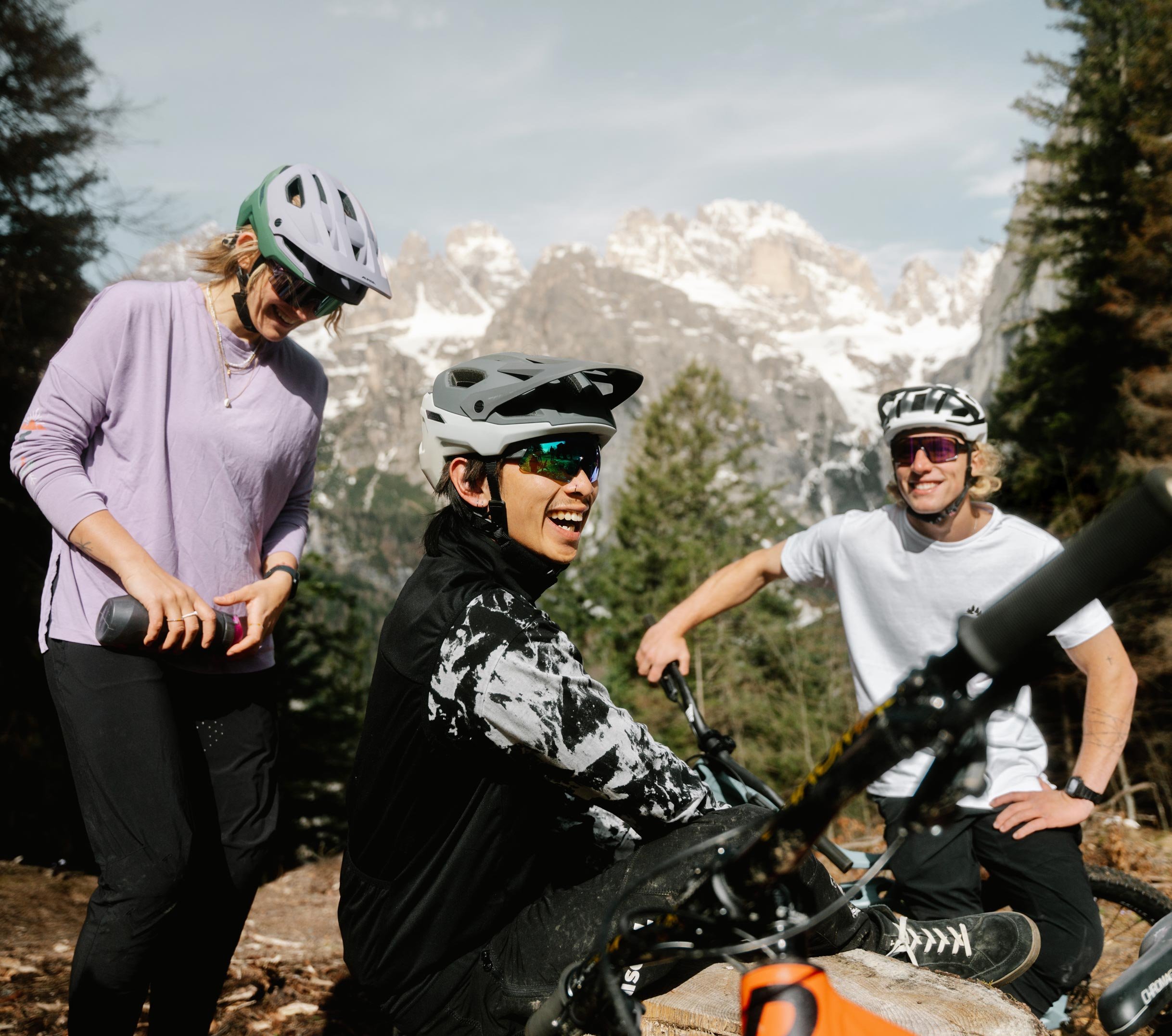 Smiling mountain bikers wearing the Alpina Rootage 2 Mips helmet during a break in the mountains.