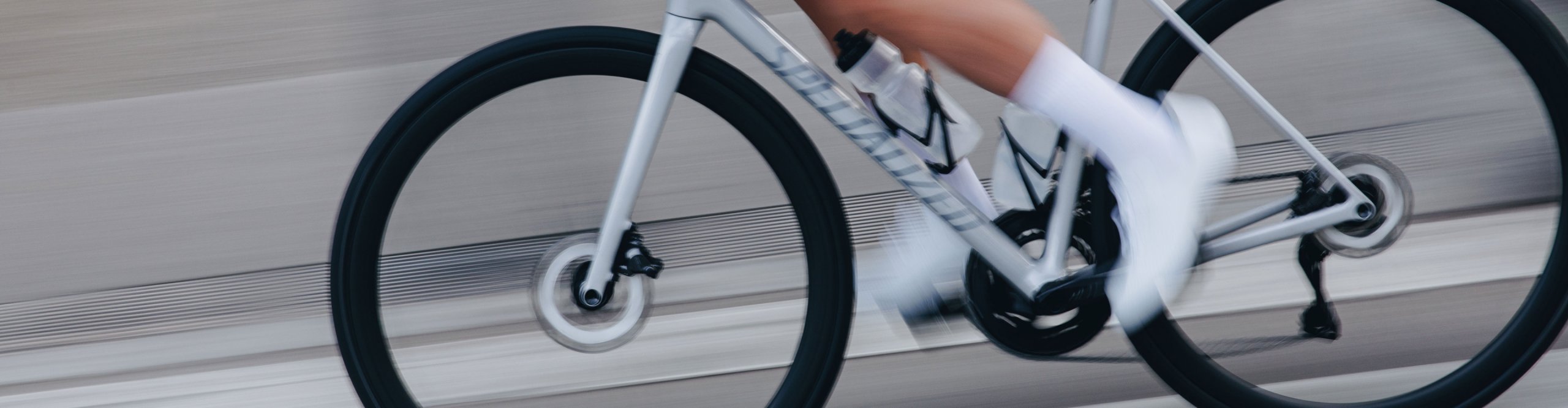 Rennradfahrer auf einem Specialized Rennrad in Seitenansicht, dynamische Fahrt auf asphaltierter Straße mit Fokus auf Rahmen, Laufräder und Sitzposition