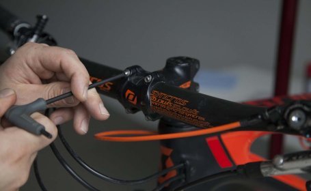 A mechanic loosens a bolt on the stem of a mountain bike.