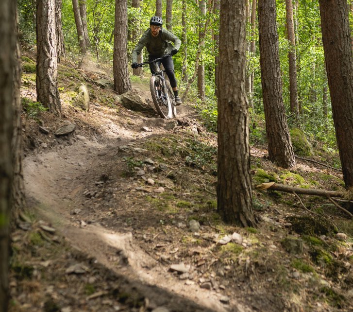 Berno fetzt auf einem Turbo Levo 4 E-MTB durch den Wald auf die Kamera zu. 