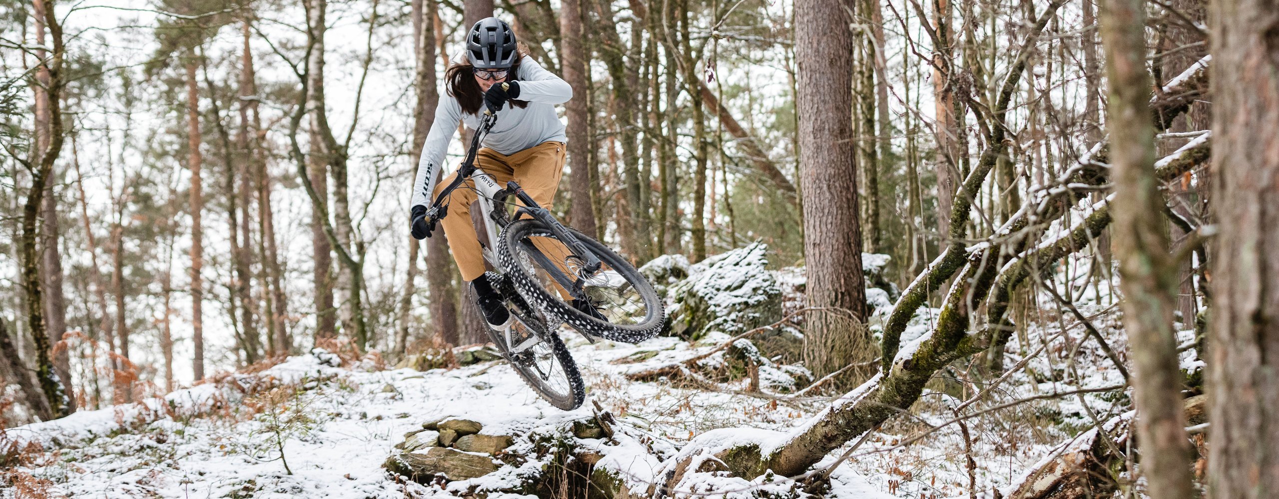 Mountainbiker fährt Trail im Wald in Winterbekleidung