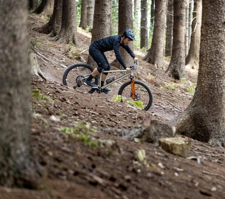 Un ciclista de montaña monta por un sendero en el bosque en una bc original Podsol.