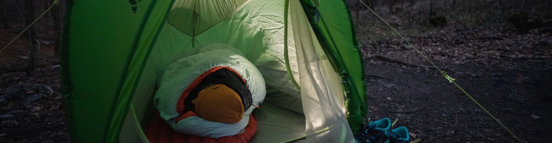 Svenja, de l'équipe de gestion de produits de bc, est chaudement emmitouflée dans son sac de couchage Deuter, dans une tente VAUDE.