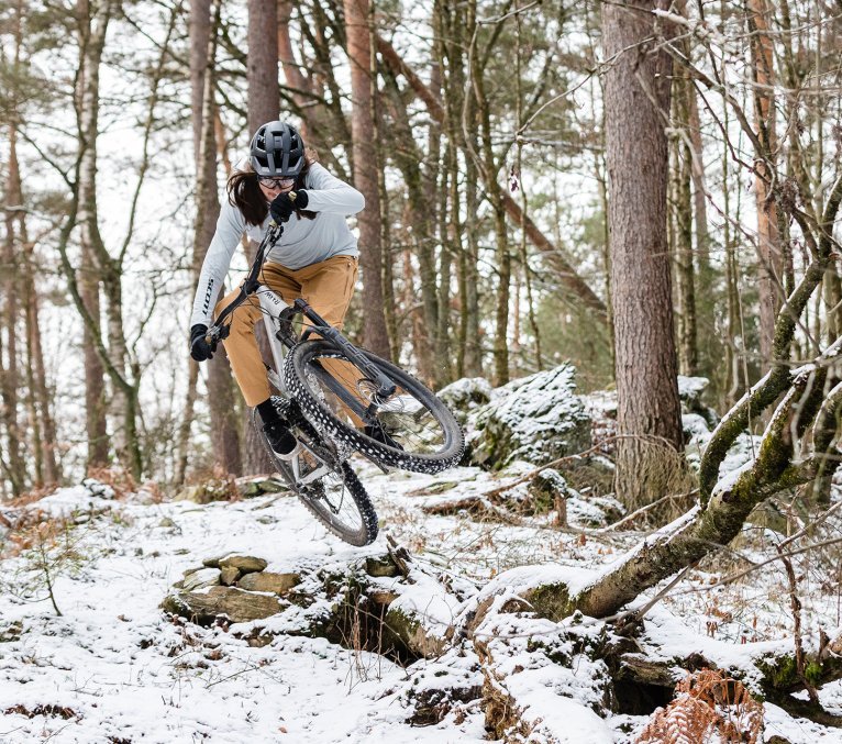 Mountainbiker fährt Trail im Wald in Winterbekleidung