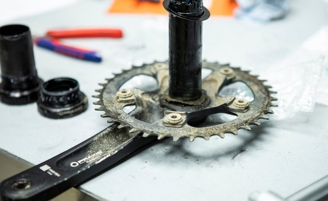 A Praxis Works crank with a fixed crankshaft is disassembled. Next to it is the matching bottom bracket. 